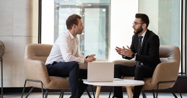 Dos hombres de traje y camisa conversando sobre los procesos de headhunting para empresas