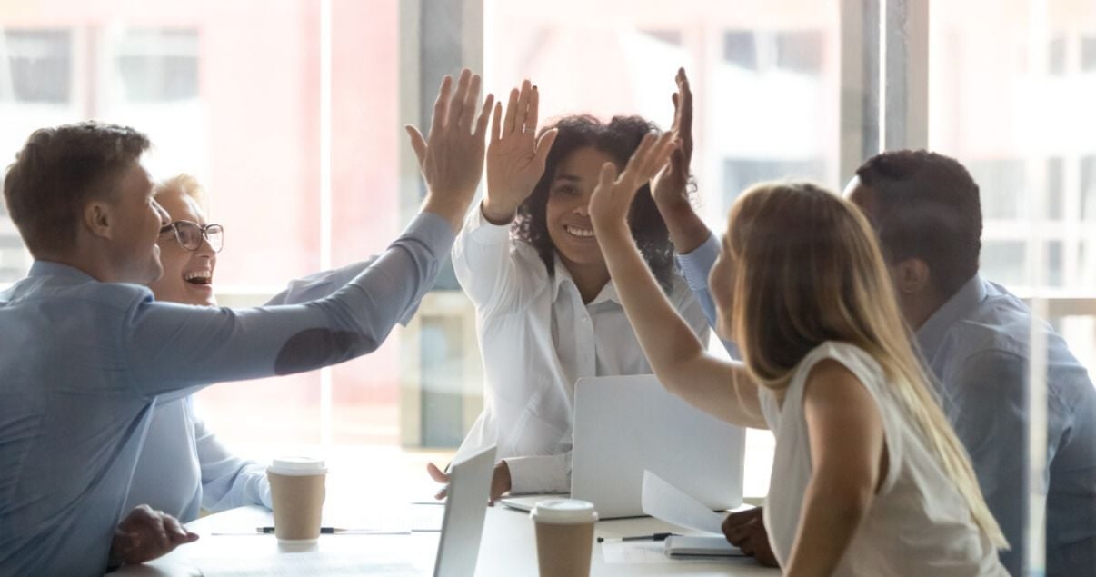 Equipo de trabajo chocando las manos luego de un proyecto exitoso de liderazgo y multiculturalidad