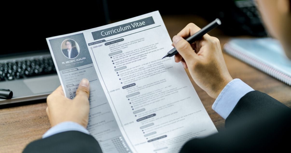 Hombre de traje usando una pluma para leer su CV y cambiar de empleo en tiempos de Coronavirus