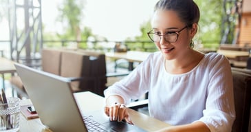 Mujer jóven con anteojos teniendo una reunión con su grupo de trabajo mientras hace teletrabajo
